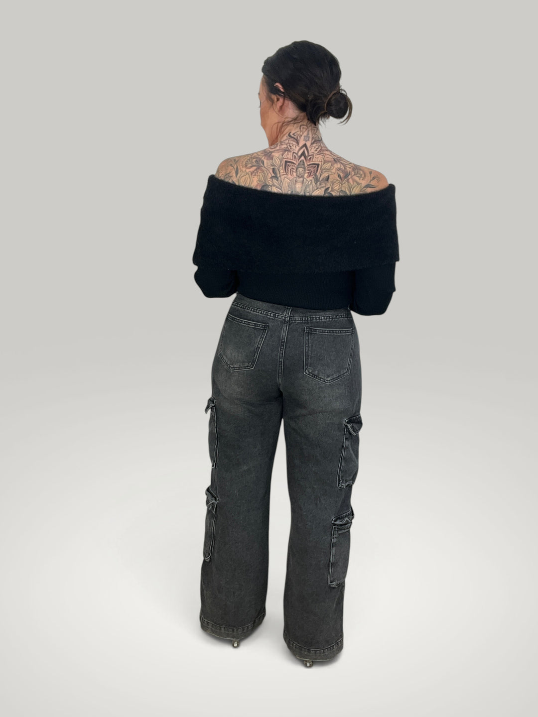 Modelo de costas vestindo blusa preta Isabelle Hannover off-shoulder de tecido macio e mangas compridas