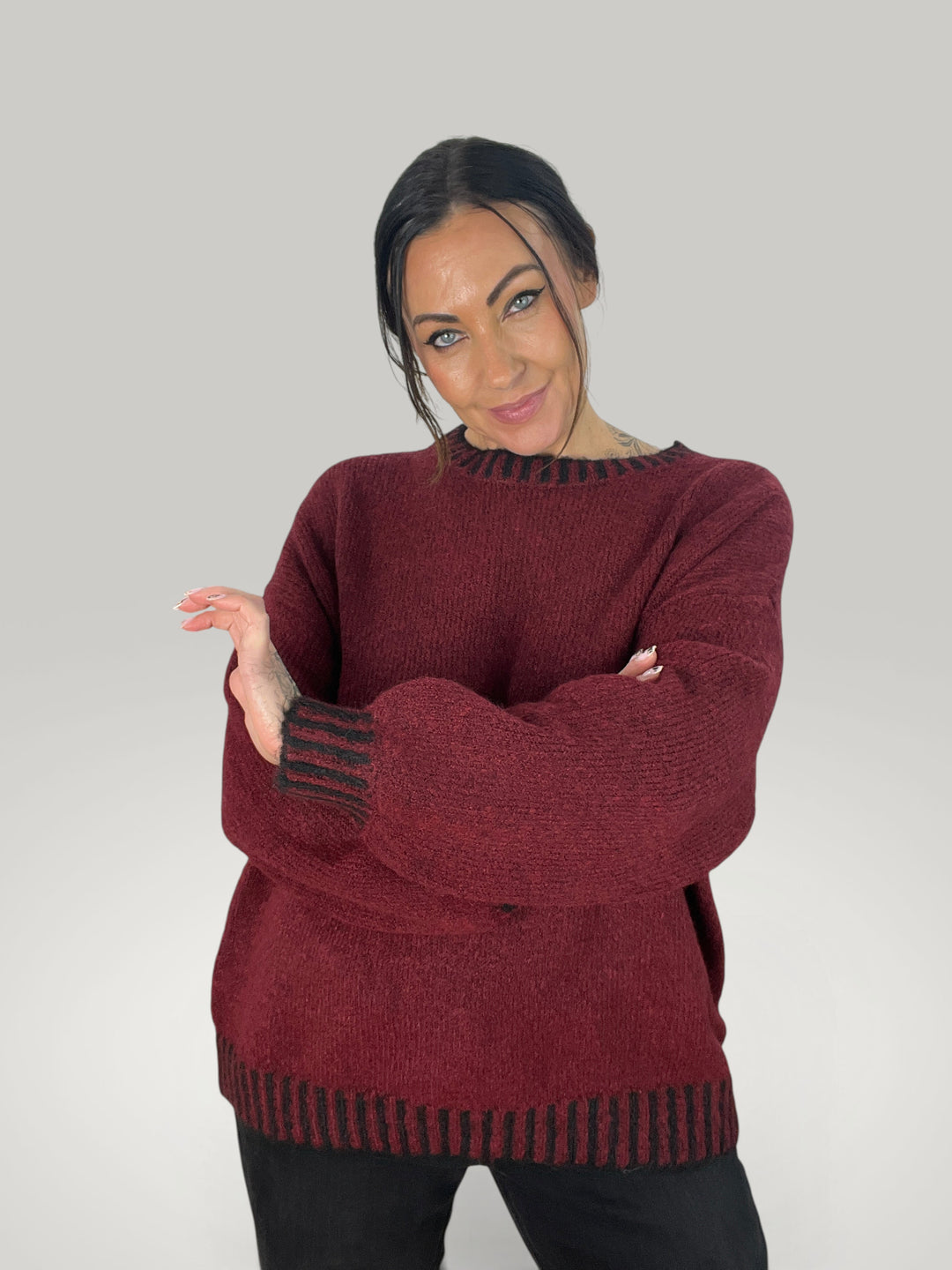 Modelo veste camisola de malha Isabelle Hannover bordô com riscas pretas contrastantes no decote, punhos e bainha.