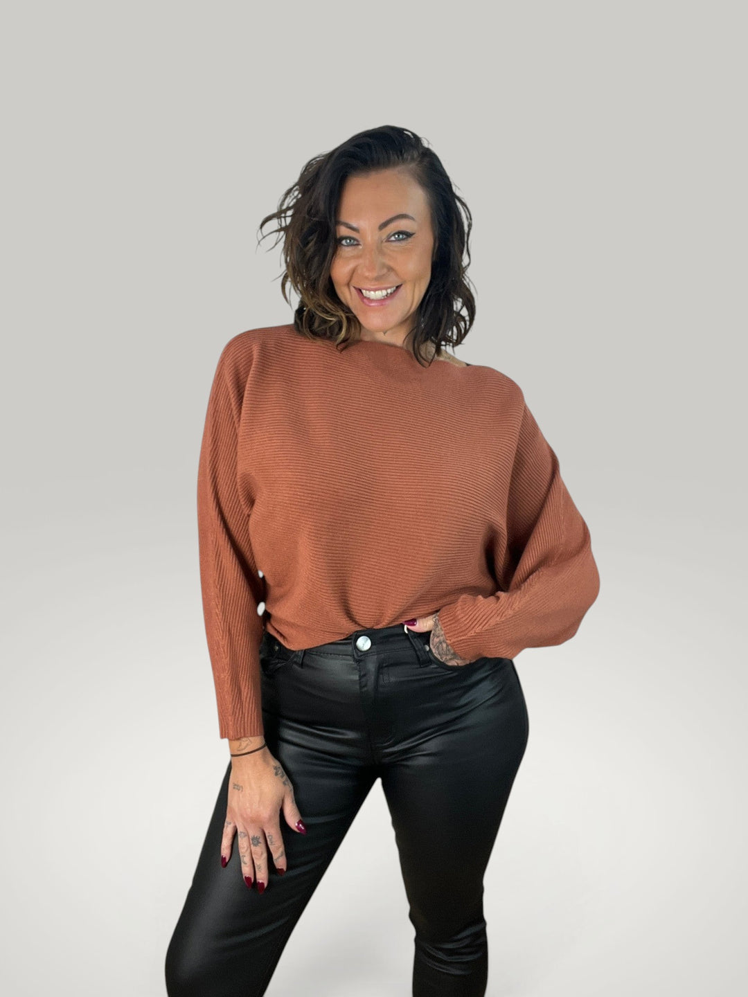 Modelo sorridente veste camisola de malha Isabelle Hannover castanha com decote barco e mangas morcego