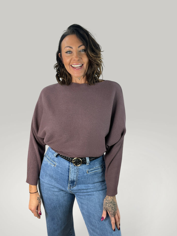 Isabelle Hannover camisola de malha castanha com decote barco, corte largo e mangas morcego em modelo sorridente