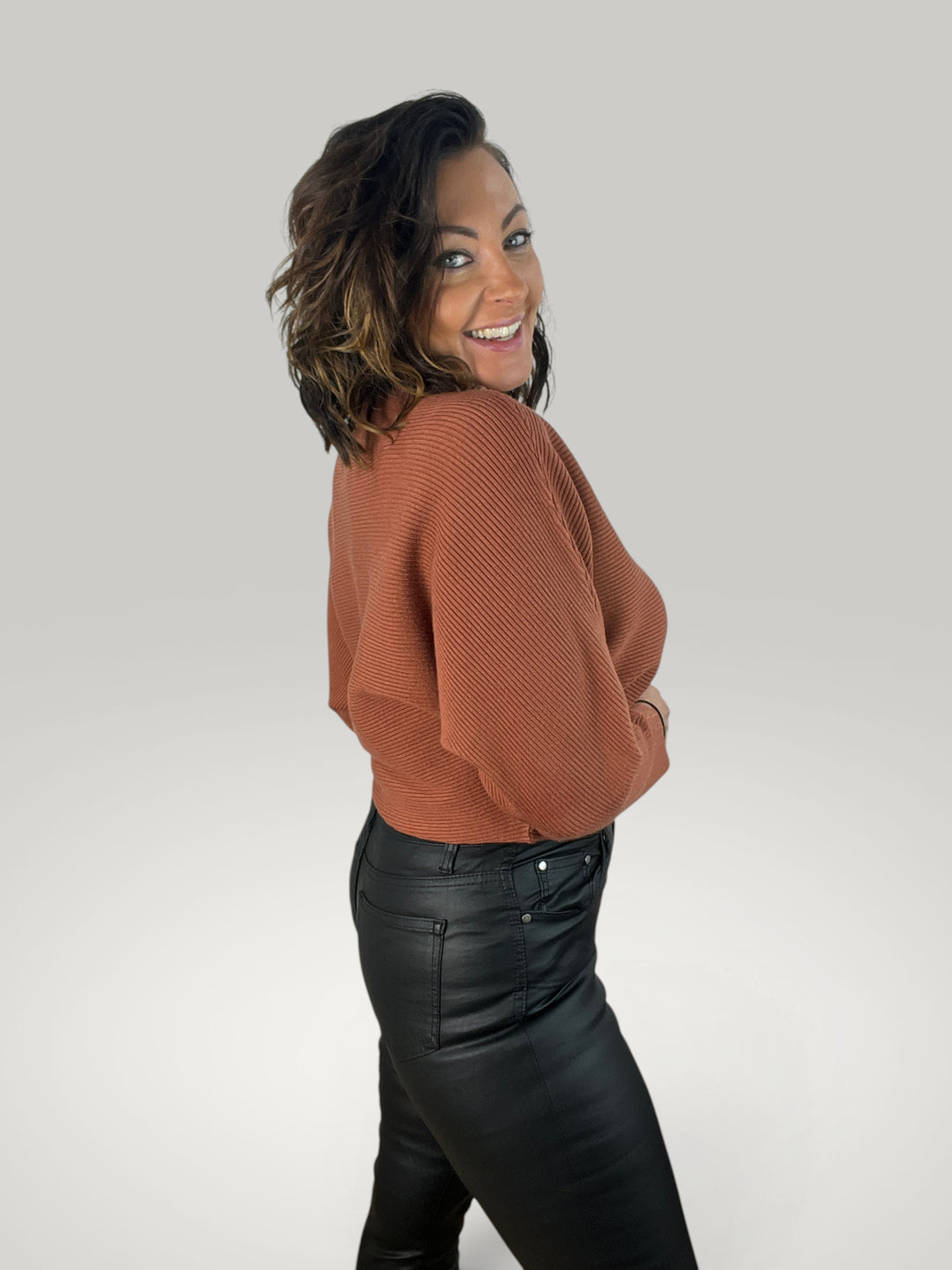 Modelo sorridente veste camisola de malha Isabelle Hannover castanha com decote barco e mangas morcego