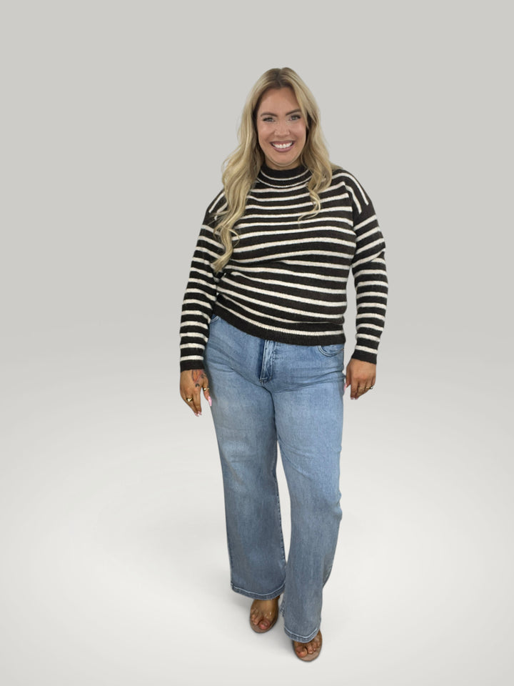 Modelo sorridente veste camisola de malha às riscas Isabelle Hannover com gola alta e corte largo e descontraído