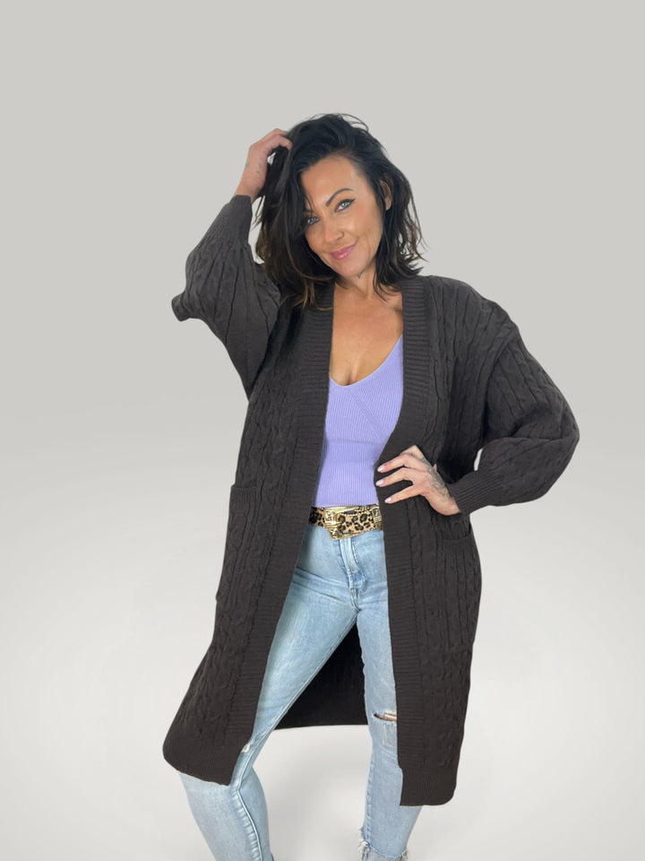 Modelo veste cardigan Isabelle Hannover castanho em malha trançada com corte largo e mangas compridas