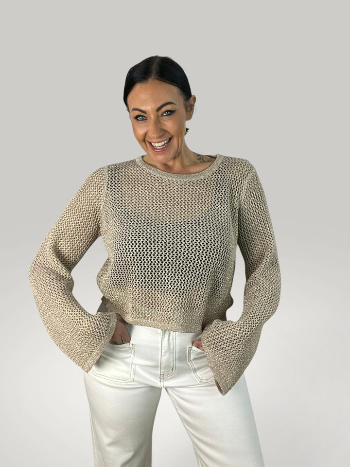 Modelo sorridente veste Isabelle Hannover crop top de crochê bege com mangas sino e gola redonda canelada