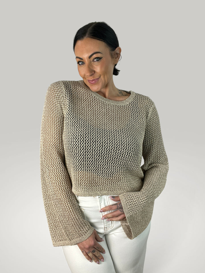 Modelo veste Isabelle Hannover crop top de croché bege com mangas largas e decote redondo em fundo neutro
