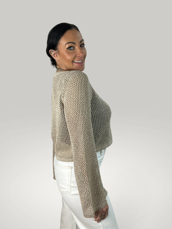 Modelo sorridente veste crop top de croché bege Isabelle Hannover com mangas largas e gola redonda