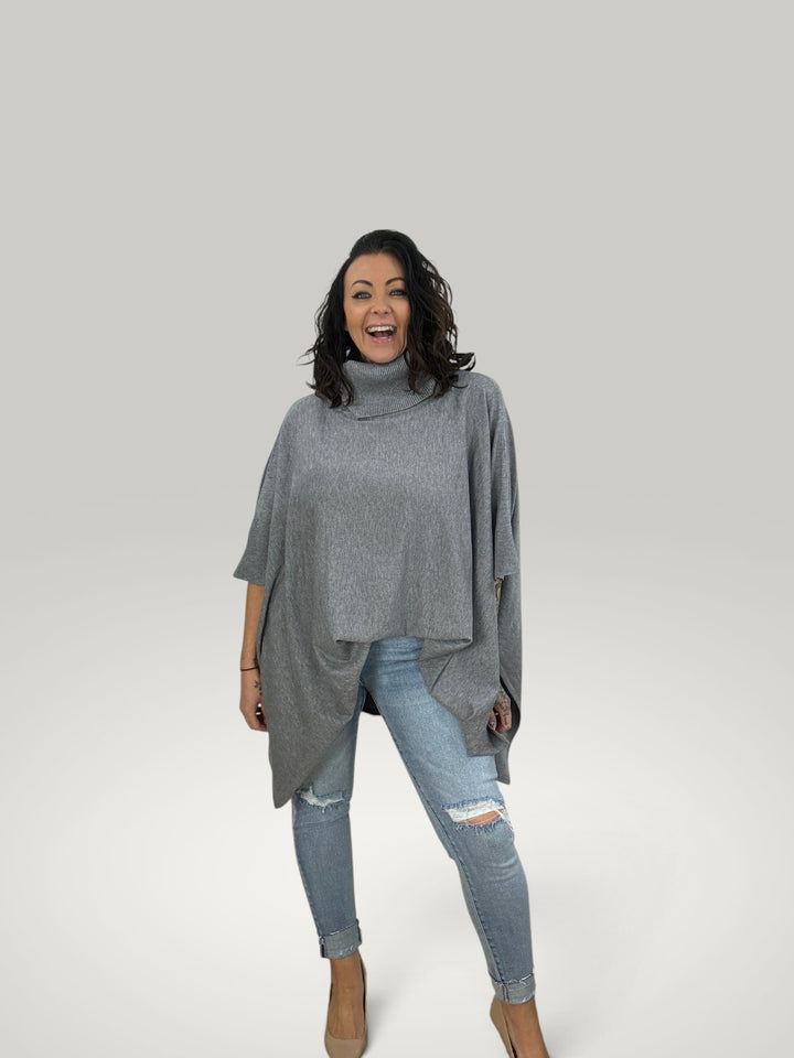 Modelo sorridente veste poncho cinzento Isabelle Hannover de malha suave com gola alta e corte oversized