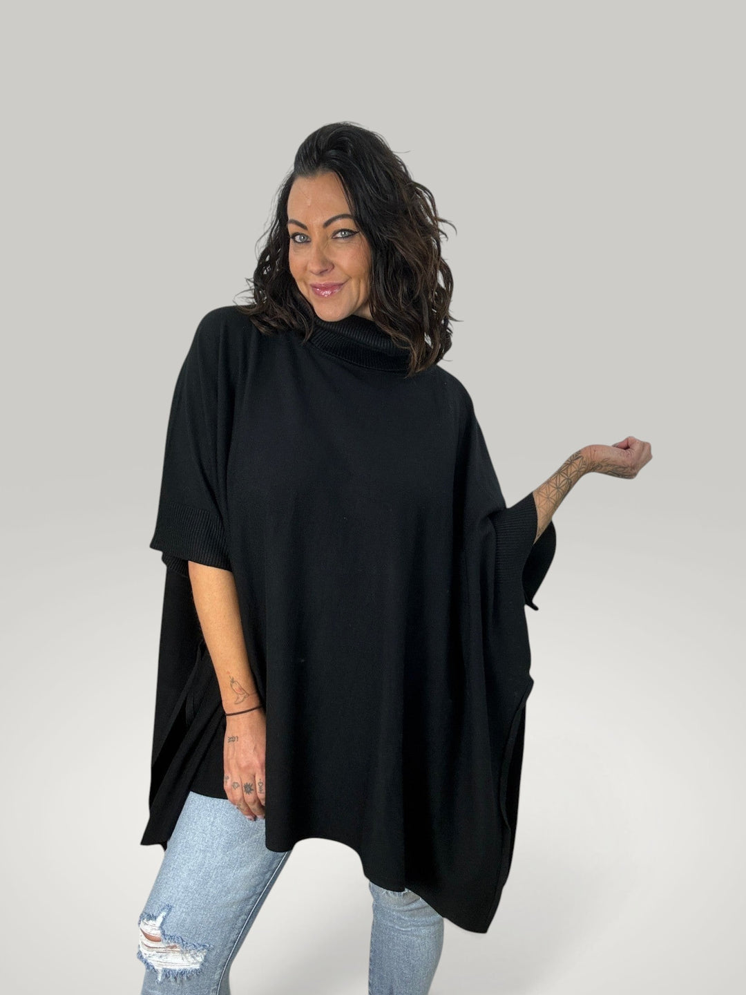 Mulher a usar poncho preto oversized Isabelle Hannover com gola alta e mangas curtas em malha macia e elástica