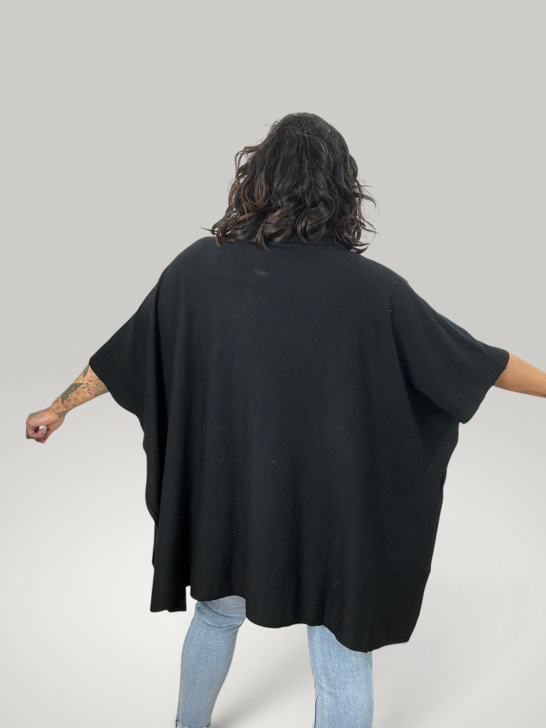Poncho preto Isabelle Hannover com gola alta, corte oversized e mangas curtas em malha macia de lã e viscose.
