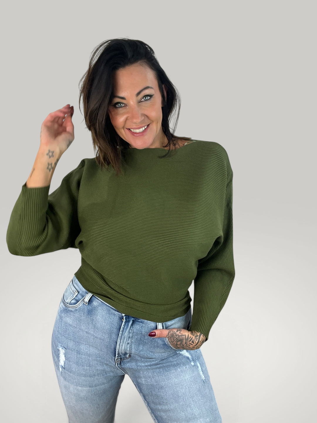 Pullover de malha verde Isabelle Hannover com decote barco e mangas morcego, usado com calças de ganga claras.