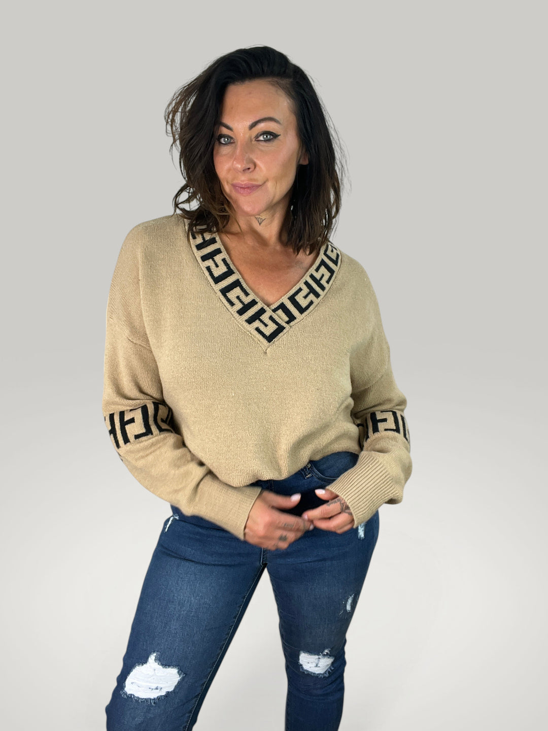 Isabelle Hannover pulôver bege com decote em V, detalhes estampados e mangas compridas em modelo vestindo jeans.