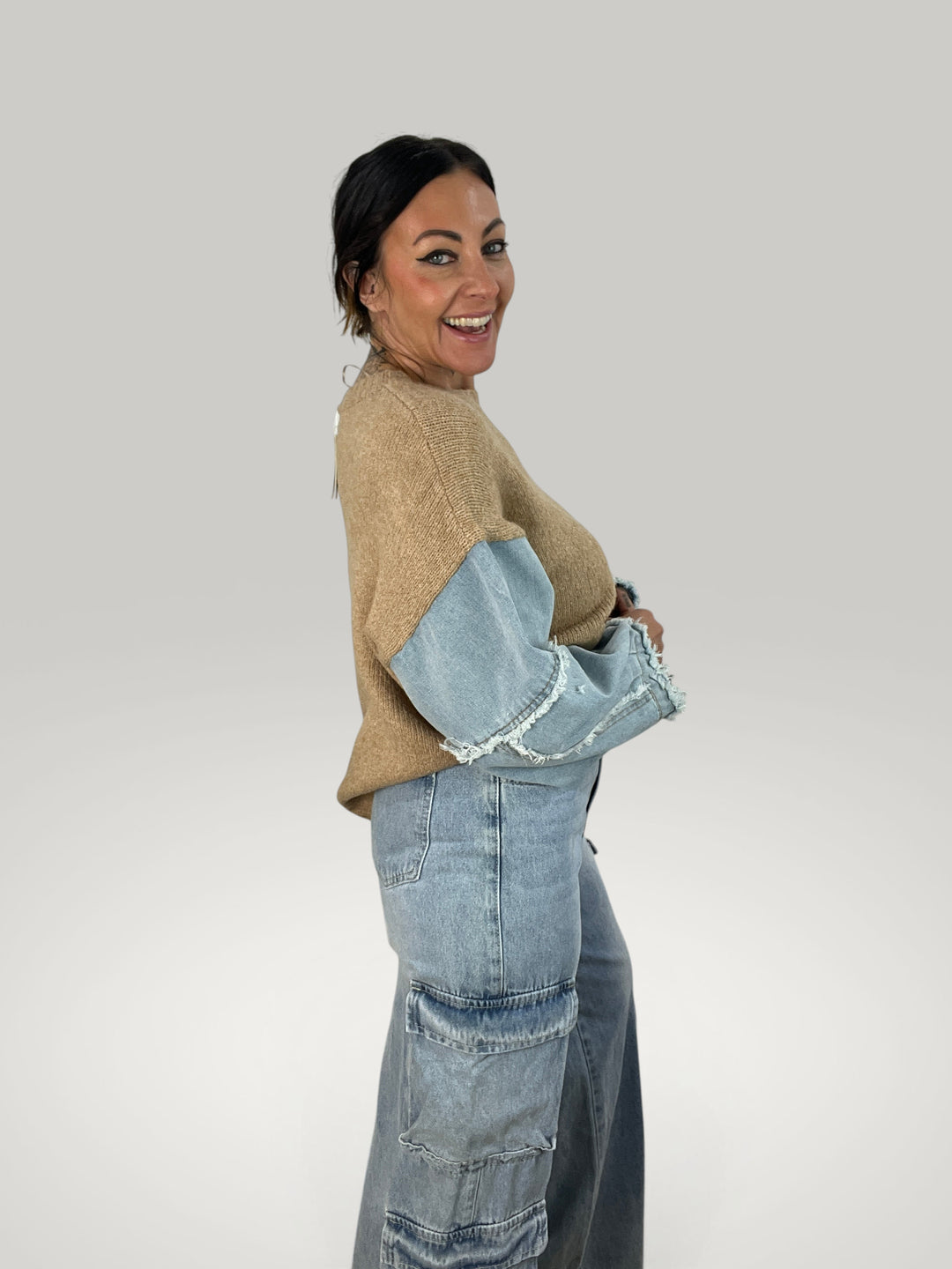 Isabelle Hannover pulôver bege com mangas de ganga contrastantes e bordas desfiadas em modelo sorridente