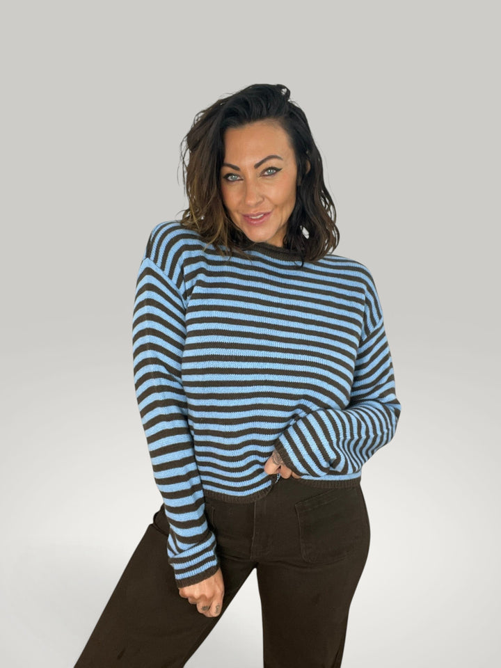 Modelo veste Isabelle Hannover pulôver cropped de malha listrada azul e marrom com gola redonda e ombros caídos