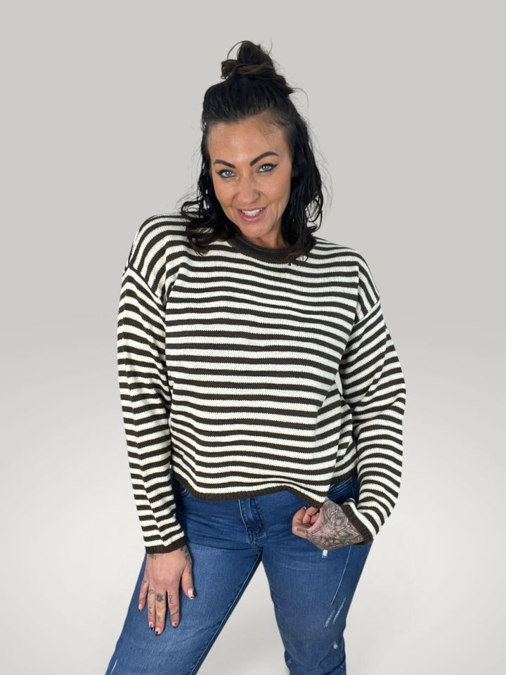 Modelo veste pulôver cropped Isabelle Hannover listrado em castanho e creme com gola redonda e ombros caídos