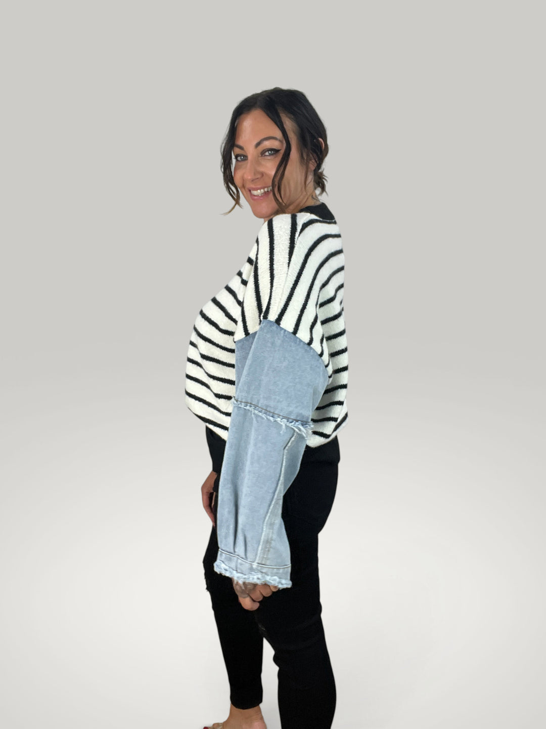 Modelo veste pulôver Isabelle Hannover listrado com mangas de ganga contrastantes e gola redonda em fundo neutro