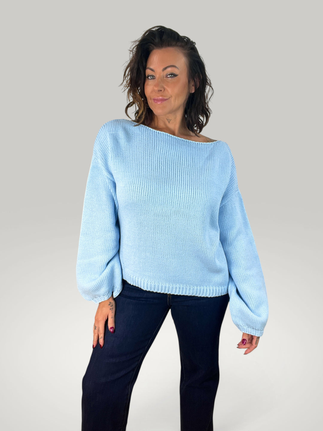 Modelo veste pulôver de malha azul claro Isabelle Hannover com decote redondo e mangas bufantes em corte solto.