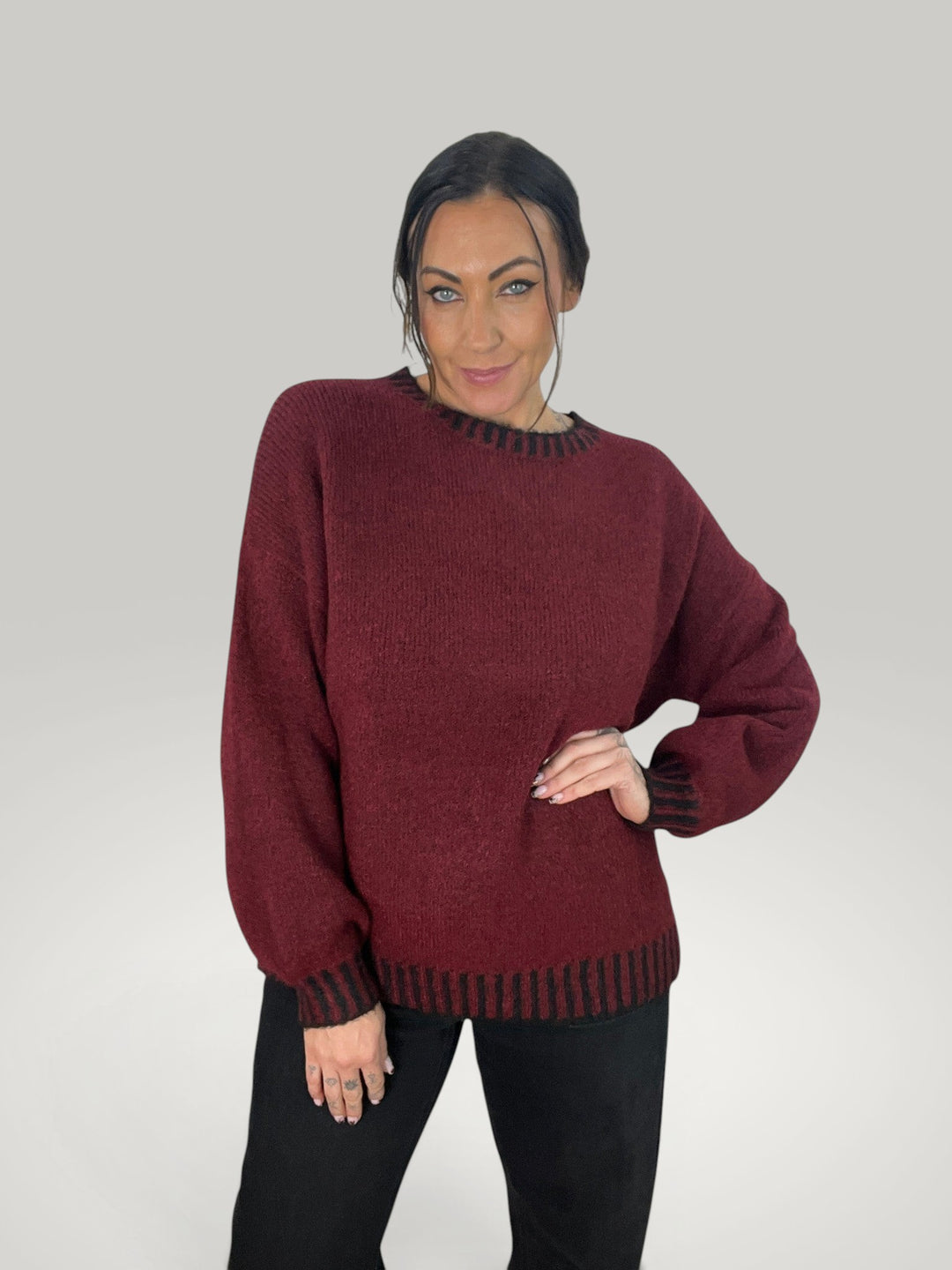 Modelo veste pulôver de malha Isabelle Hannover bordô com gola redonda e detalhes em listras pretas contrastantes