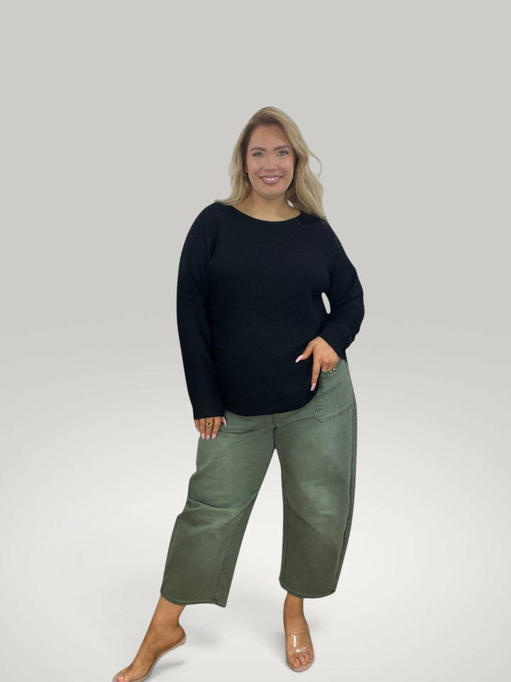 Modelo loira veste pulôver de malha preto Isabelle Hannover com decote redondo e bainha assimétrica