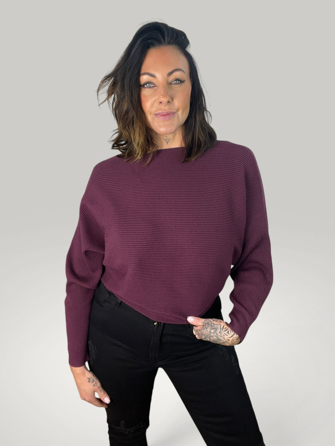 Modelo veste pulôver de malha Isabelle Hannover roxo com decote canoa e mangas morcego em corte quadrado