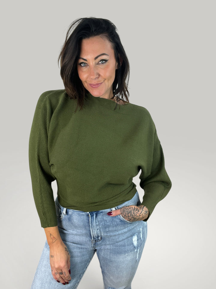 Modelo veste pulôver de malha verde Isabelle Hannover com decote canoa, corte largo e mangas morcego.