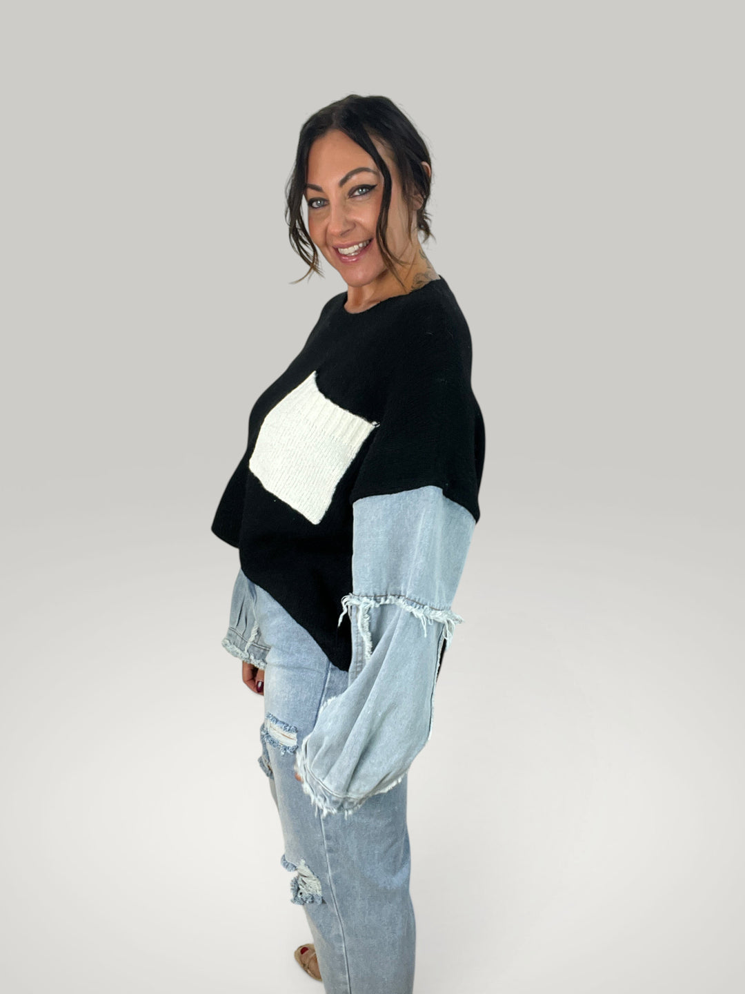 Modelo vestindo pulôver Isabelle Hannover preto com bolso branco e mangas de jeans com bordas desfiadas