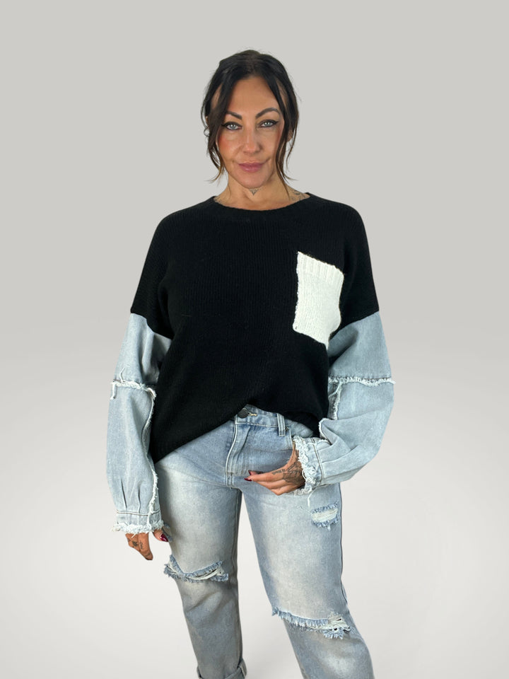 Modelo veste pulôver Isabelle Hannover preto com mangas de ganga em contraste e bolso frontal, estilo casual.