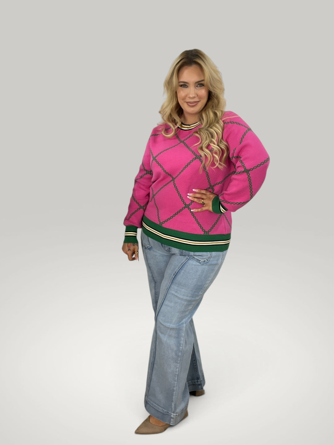 Modelo loira vestindo pulôver de tricô rosa Isabelle Hannover com padrão de correntes e detalhes em verde e branco