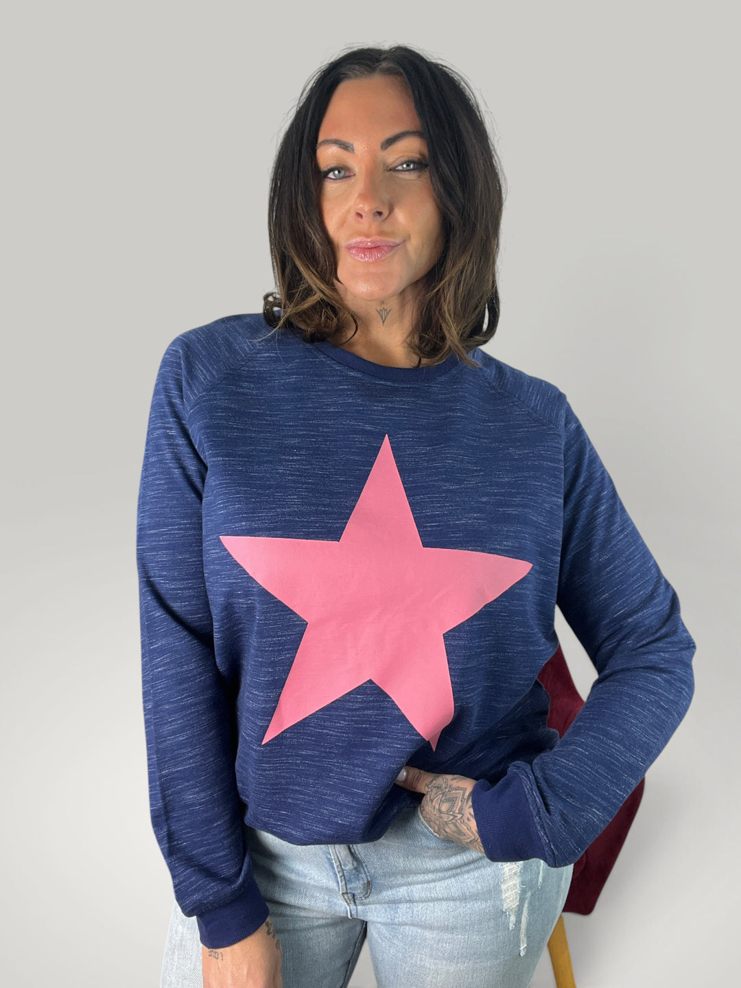 Mulher vestindo sweatshirt Isabelle Hannover azul com estampa de estrela rosa, gola redonda e corte descontraído.