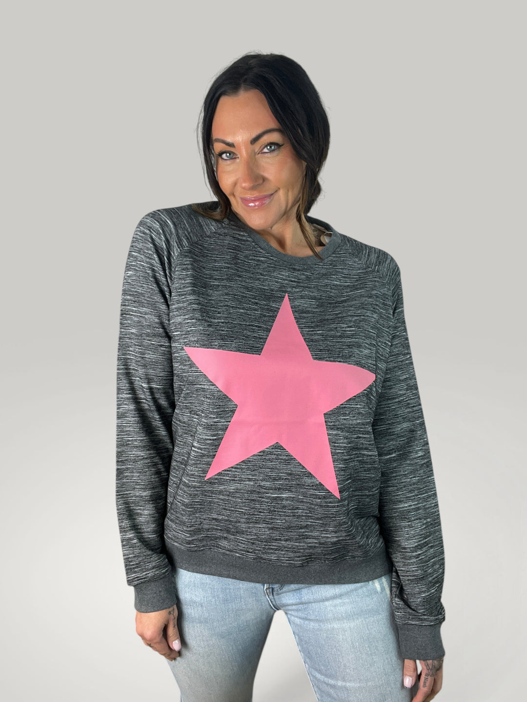 Modelo veste sweatshirt Isabelle Hannover cinzenta com estampado de estrela rosa, corte largo e decote redondo.