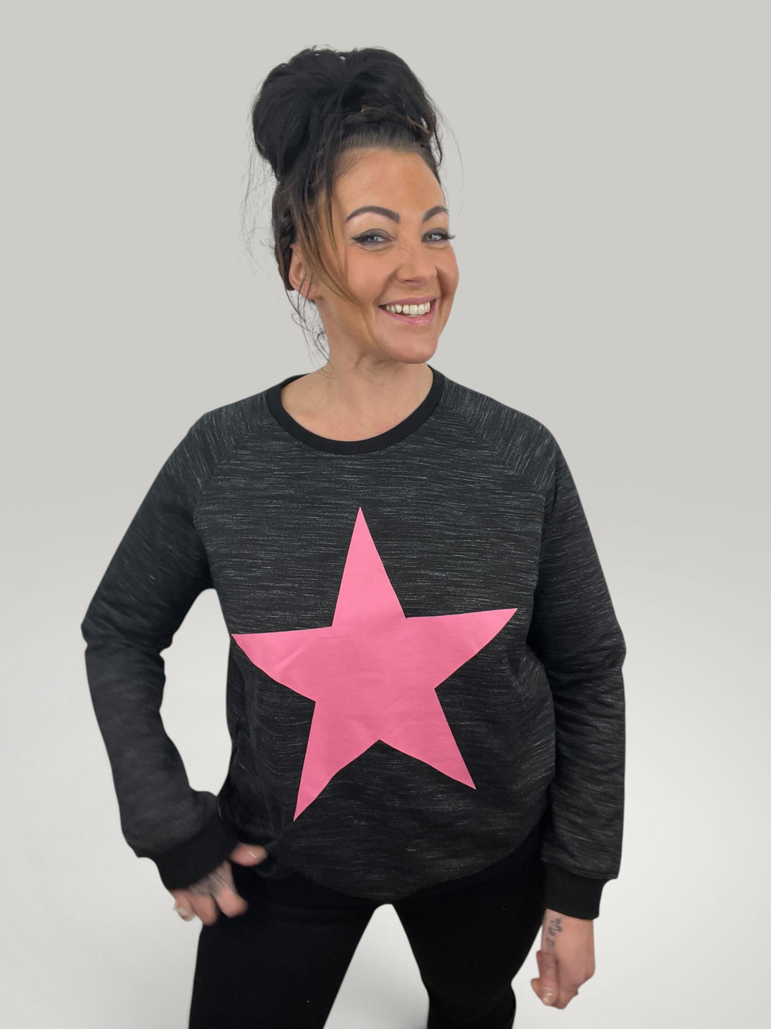 Modelo sorridente veste sweatshirt Isabelle Hannover preta com estampa de estrela rosa em algodão de corte largo