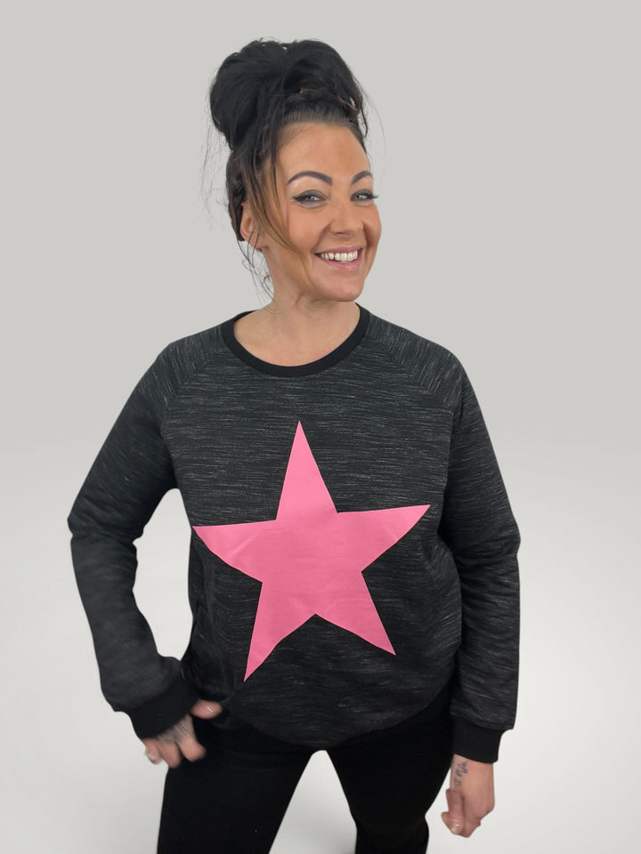 Modelo sorridente veste sweatshirt Isabelle Hannover preta com estampa de estrela rosa em algodão de corte largo