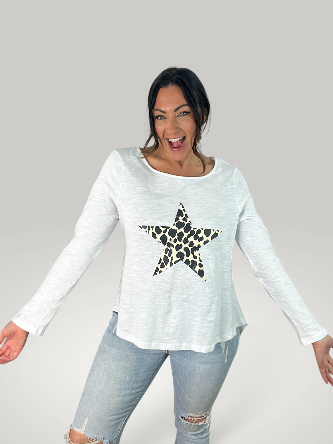 Mulher sorridente veste t-shirt de manga comprida Isabelle Hannover branca com estampa de estrela em padrão animal