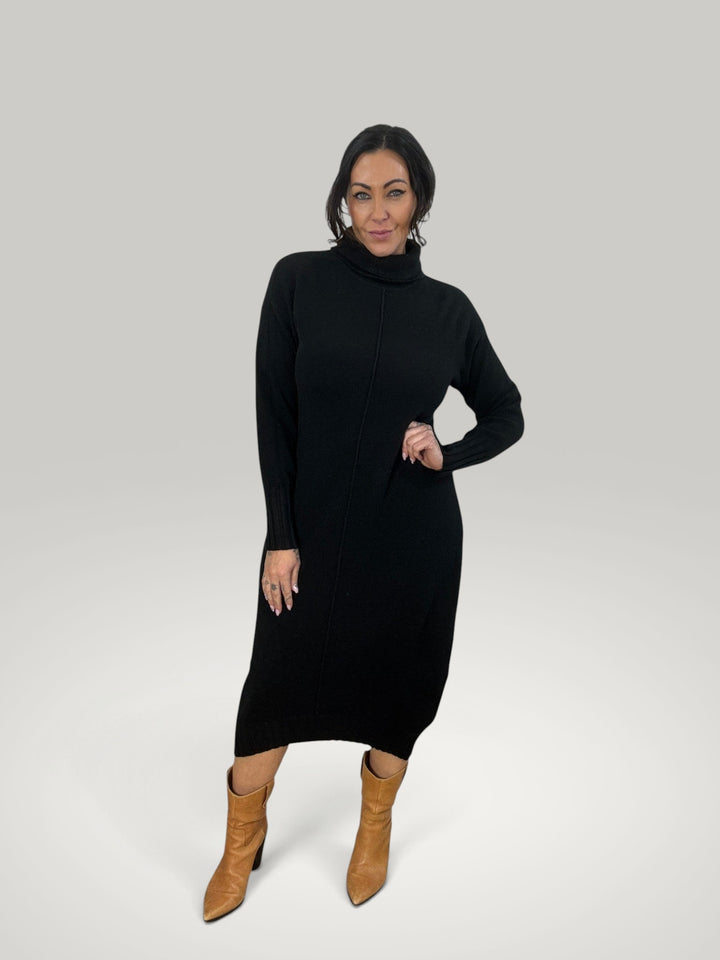 Modelo veste vestido midi de malha preta Isabelle Hannover com gola alta e mangas compridas, combinado com botas.