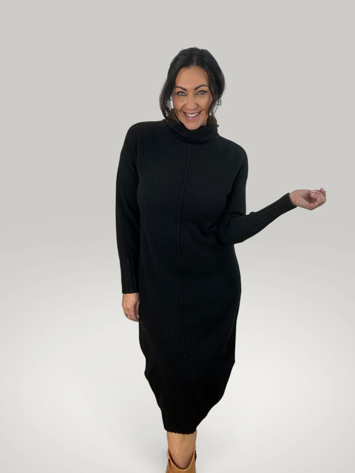 Modelo sorridente vestindo vestido de malha preto Isabelle Hannover com gola alta e mangas compridas